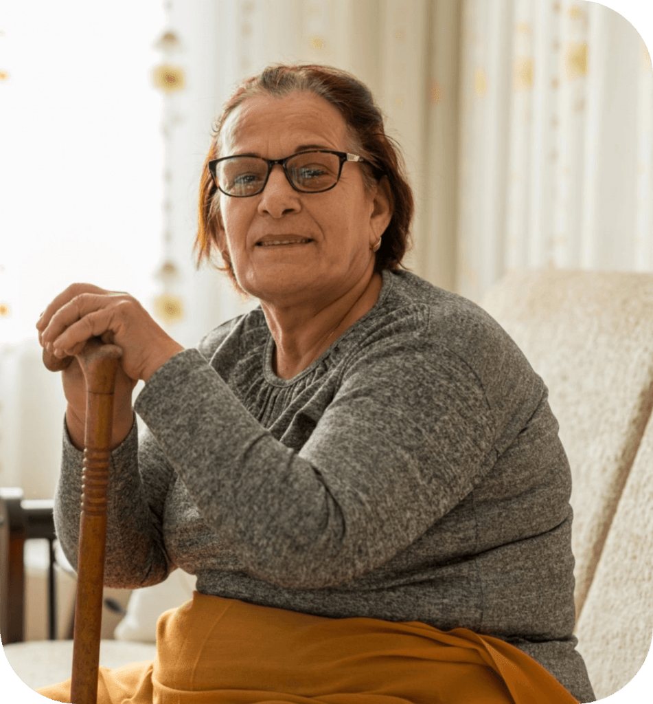 SIL vacan | An old lady with disabilities sitting on a couch with a smile, SIL Bayswater